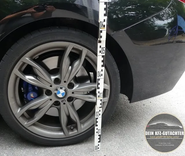 Dein Kfz-Gutachter macht eine Schadenaufnahme mit Maßband an einem Auto nach einem Unfall für ein Kfz-Gutachten